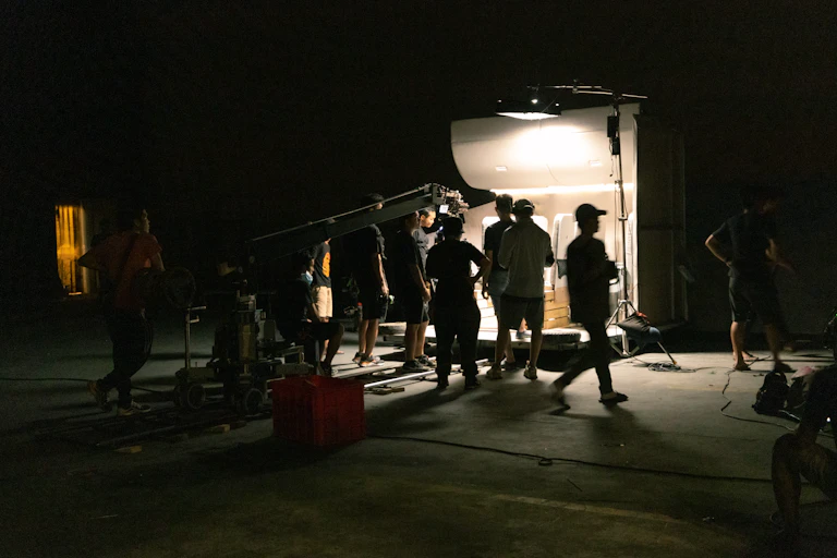 Film set under construction on a sound stage, with lighting rig, truss structures and production crew